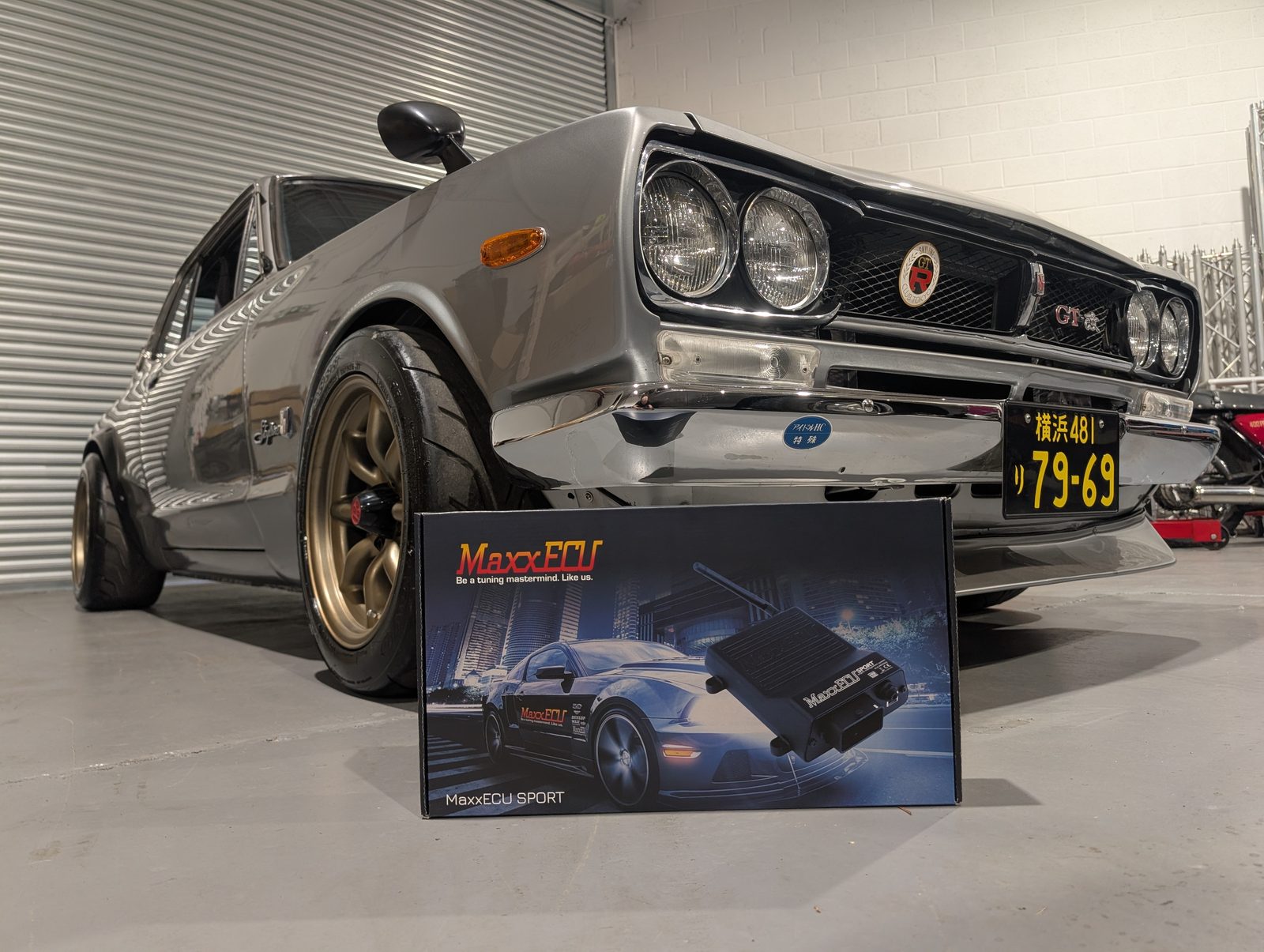 A silver Nissan Skyline GT-R in the workshop with a MaxxECU Sport box in front of the front wheel